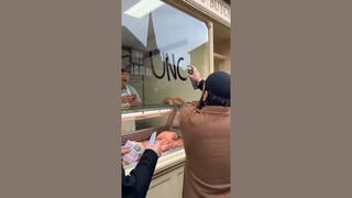 Fact Check: Fake Video Shows A Man In A Muslim Mob Spray Painting A Butcher Shop Window In England -- AI-Generated With Many Glitches